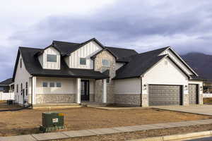 Modern farmhouse with board and batten siding, stone siding, a shingled roof, driveway, and a porch