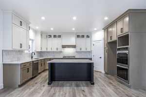 Kitchen with light stone counters, a kitchen island, stainless steel appliances, light wood-style flooring, and recessed lighting