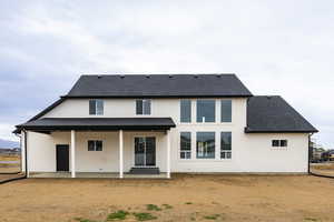 Rear view of house featuring roof with shingles and a patio area