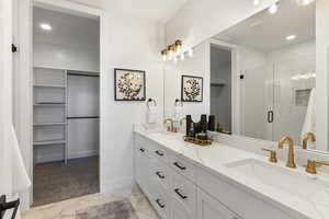 Full bathroom featuring a walk in closet, recessed lighting, double vanity, a stall shower, and light marble finish flooring