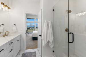 Full bath featuring ensuite bathroom, a mountain view, vanity, light marble finish floors, and a stall shower