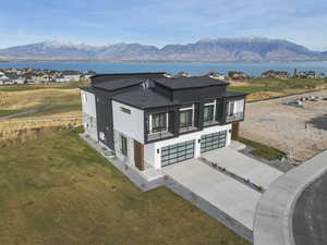 View of front of home featuring stone siding, driveway, a garage, a front lawn, and roof with shingles