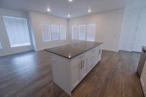Kitchen featuring white cabinetry, dark wood-style flooring, dishwasher, recessed lighting, and a center island