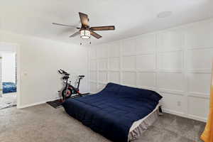 Bedroom featuring carpet flooring, a ceiling fan, and a decorative wall