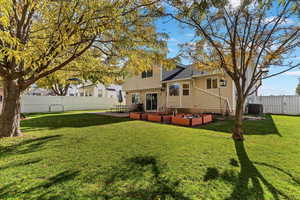 Rear view of house with a fenced backyard, a vegetable garden, and a patio