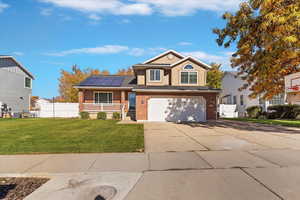 View of front of home featuring brick siding, driveway, solar panels, and covered porch