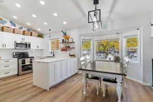 Kitchen featuring pendant lighting, decorative backsplash, appliances with stainless steel finishes, recessed lighting, and white cabinets