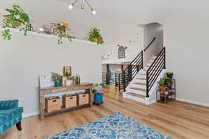 Entryway with stairway, light wood-style floors, a chandelier, and a towering ceiling