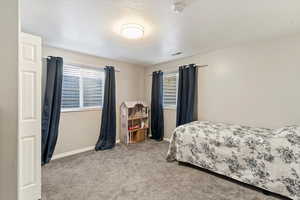 Carpeted bedroom featuring baseboards and a textured ceiling