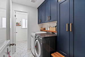 Laundry room featuring light tile patterned flooring, cabinet space, and washer and clothes dryer