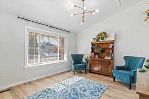 Living area featuring lofted ceiling, light wood-type flooring, and a chandelier