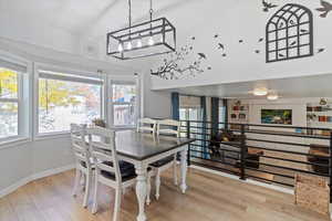 Dining area with light wood-style flooring and a towering ceiling