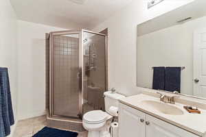 Full bath with vanity, a stall shower, and light tile patterned floors