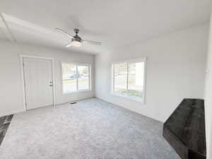 Unfurnished living room featuring carpet flooring and a ceiling fan