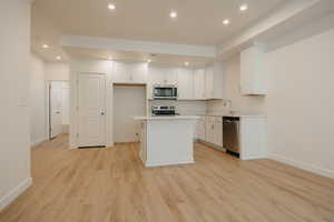 Kitchen featuring white cabinets, a kitchen island, light wood-style flooring, recessed lighting, and stainless steel appliances