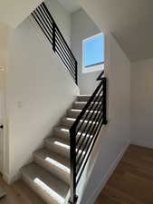 Stairs featuring wood finished floors and a high ceiling