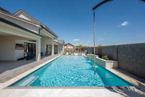 View of pool with a patio, a fenced backyard, and a pool with connected hot tub