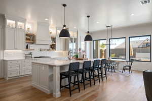 Kitchen with a kitchen breakfast bar, hanging light fixtures, tasteful backsplash, light wood-type flooring, and recessed lighting