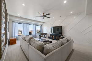 Living room featuring a decorative wall, light carpet, recessed lighting, and a ceiling fan