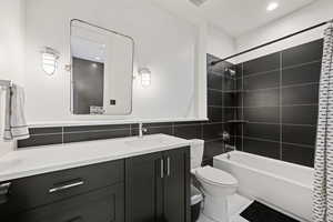 Bathroom with vanity, tile walls,  shower combination, light tile patterned floors, and recessed lighting