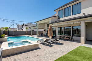 View of swimming pool featuring a patio, a pool with connected hot tub, outdoor dining area, and a fenced backyard
