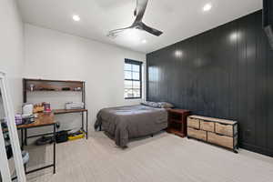 Carpeted bedroom featuring ceiling fan, wooden walls, recessed lighting, and an office area