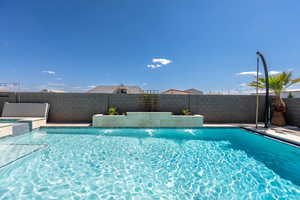 View of pool featuring a fenced backyard, a pool with connected hot tub, and a patio