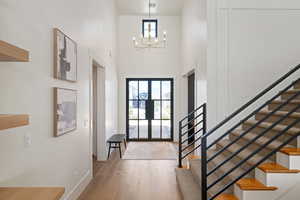 Entryway featuring a high ceiling, wood finished floors, stairway, and a chandelier