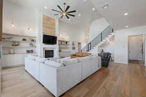 Living area featuring recessed lighting, light wood-style floors, a tiled fireplace, stairs, and ceiling fan