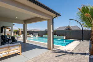 View of swimming pool with a patio area, a fenced backyard, and a pool with connected hot tub