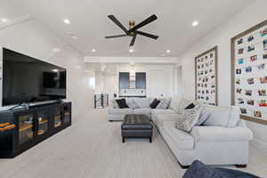 Living area featuring light colored carpet, recessed lighting, a decorative wall, and a ceiling fan