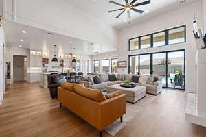 Living room featuring recessed lighting, light wood-style floors, a high ceiling, and a ceiling fan