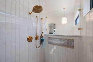 Bathroom featuring tiled shower and a chandelier