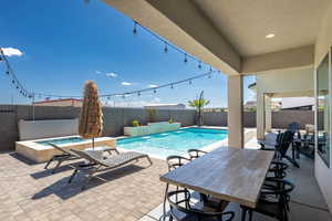 View of swimming pool featuring a patio area, a fenced backyard, an in-ground hot tub, and outdoor dining space