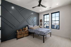 Bedroom with a decorative wall, light carpet, ceiling fan, and recessed lighting