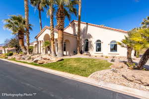 Mediterranean / spanish home featuring a front yard, a tiled roof, and stucco siding