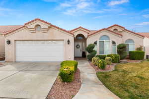 Mediterranean / spanish-style home featuring stucco siding, a front yard, a tile roof, concrete driveway, and an attached garage