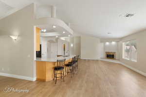 Kitchen with a kitchen breakfast bar, a peninsula, light wood finished floors, recessed lighting, and light stone counters