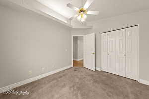 Unfurnished bedroom featuring carpet, a textured ceiling, a closet, and ceiling fan