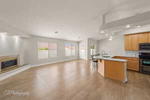 Kitchen with open floor plan, a breakfast bar, a high end fireplace, stainless steel appliances, and recessed lighting