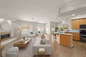 Living room featuring a premium fireplace, recessed lighting, light wood-type flooring, vaulted ceiling, and a textured ceiling