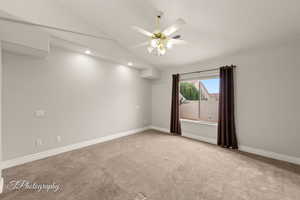 Spare room featuring vaulted ceiling, light colored carpet, ceiling fan, and recessed lighting