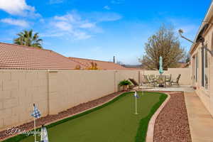 Fenced backyard featuring a patio and an area to practice putting
