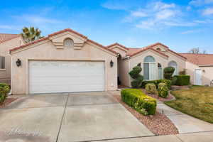 Mediterranean / spanish home with stucco siding, concrete driveway, a tile roof, an attached garage, and a front yard