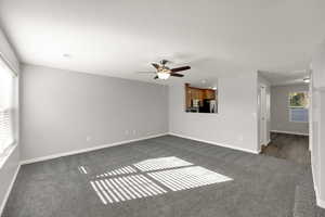 Empty room featuring dark carpet and ceiling fan