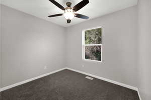 Unfurnished room featuring dark carpet and a ceiling fan