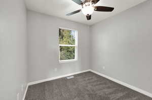 Carpeted spare room featuring baseboards and a ceiling fan