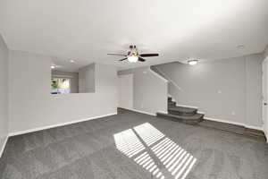 Unfurnished living room with carpet flooring, stairs, and ceiling fan