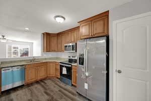 Kitchen featuring stainless steel appliances, dark wood-style floors, brown cabinetry, and recessed lighting