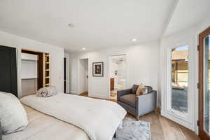 Bedroom featuring wood finished floors, a spacious closet, recessed lighting, and access to exterior